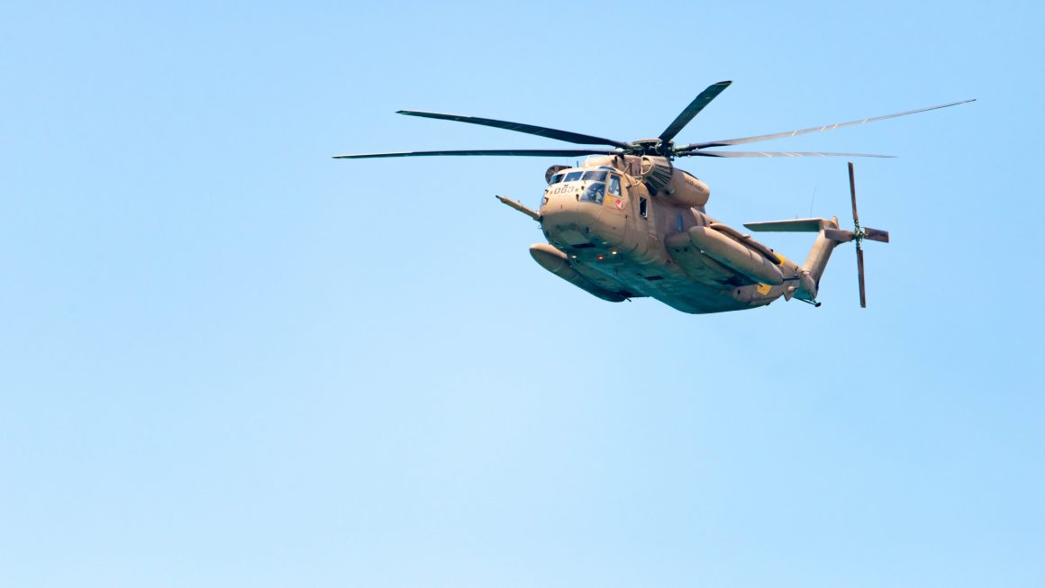 Image of helicopter in blue clear sky, flying from right to left.